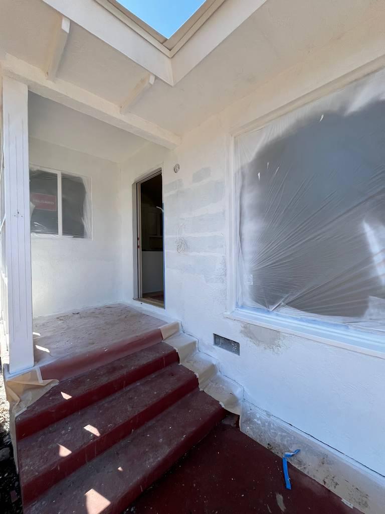 Front porch under renovation with red steps and masked windows
