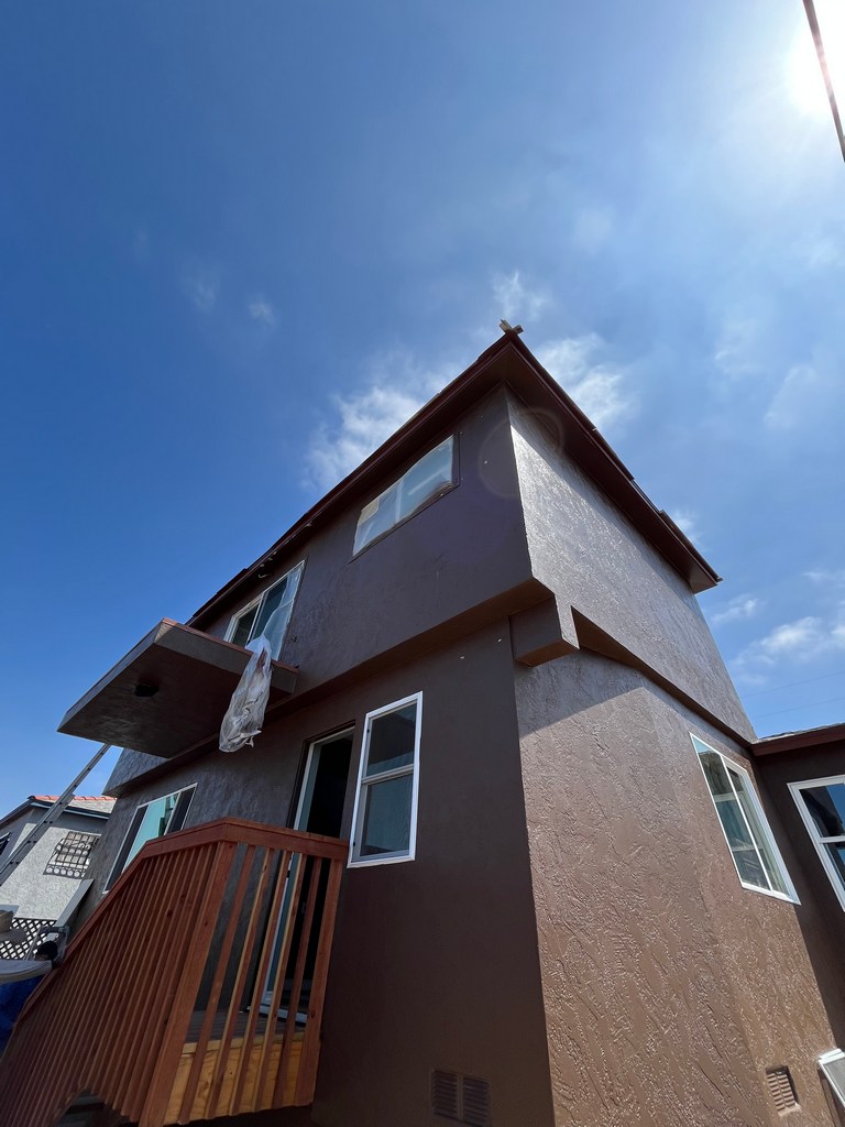Side stucco elevation with balcony, windows, stairs, and finished exterior wall texture.