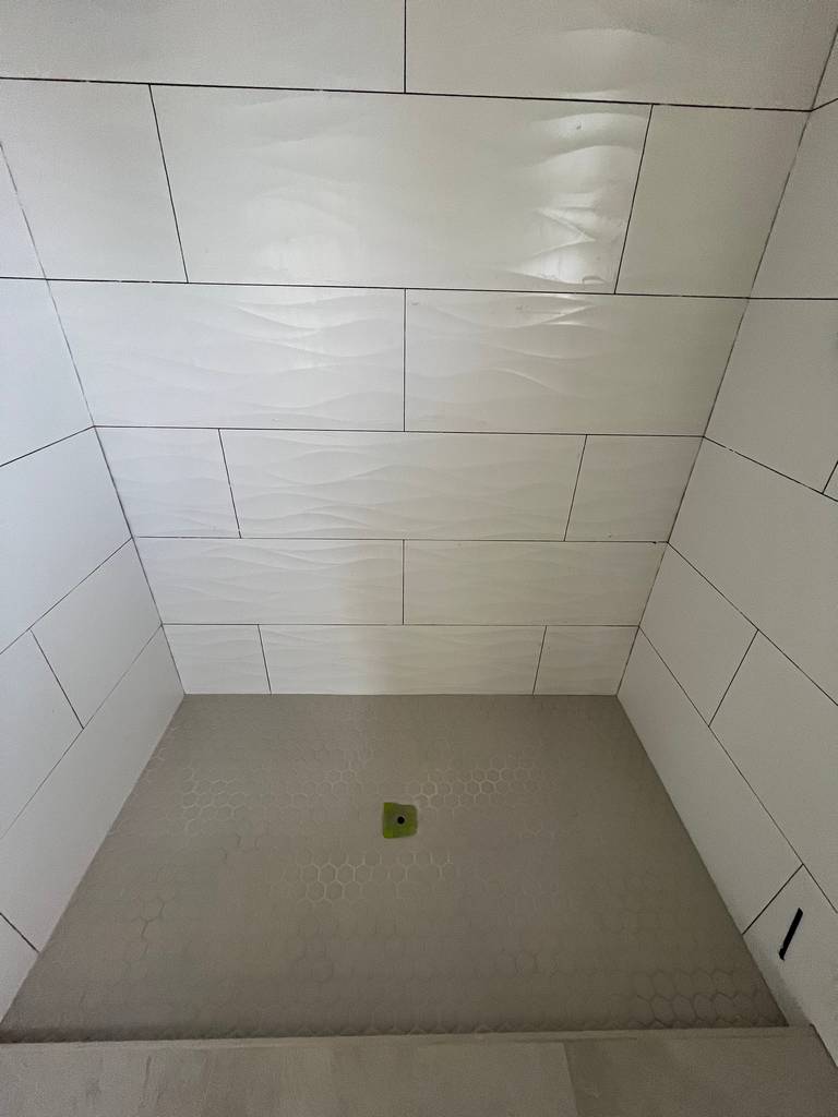 Professional tile setter finishing walk-in shower