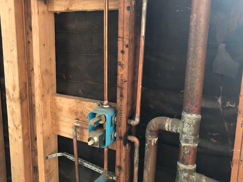 exposed wall showing copper plumbing in a bathroom remodel