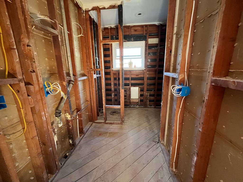 Partially renovated area with exposed insulation, framing, and rough plumbing.