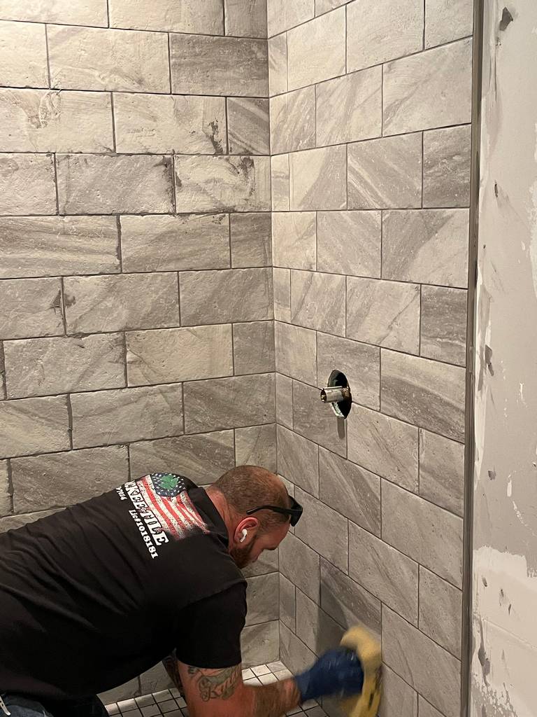 Professional tile worker applying grout between long horizontal tiles.