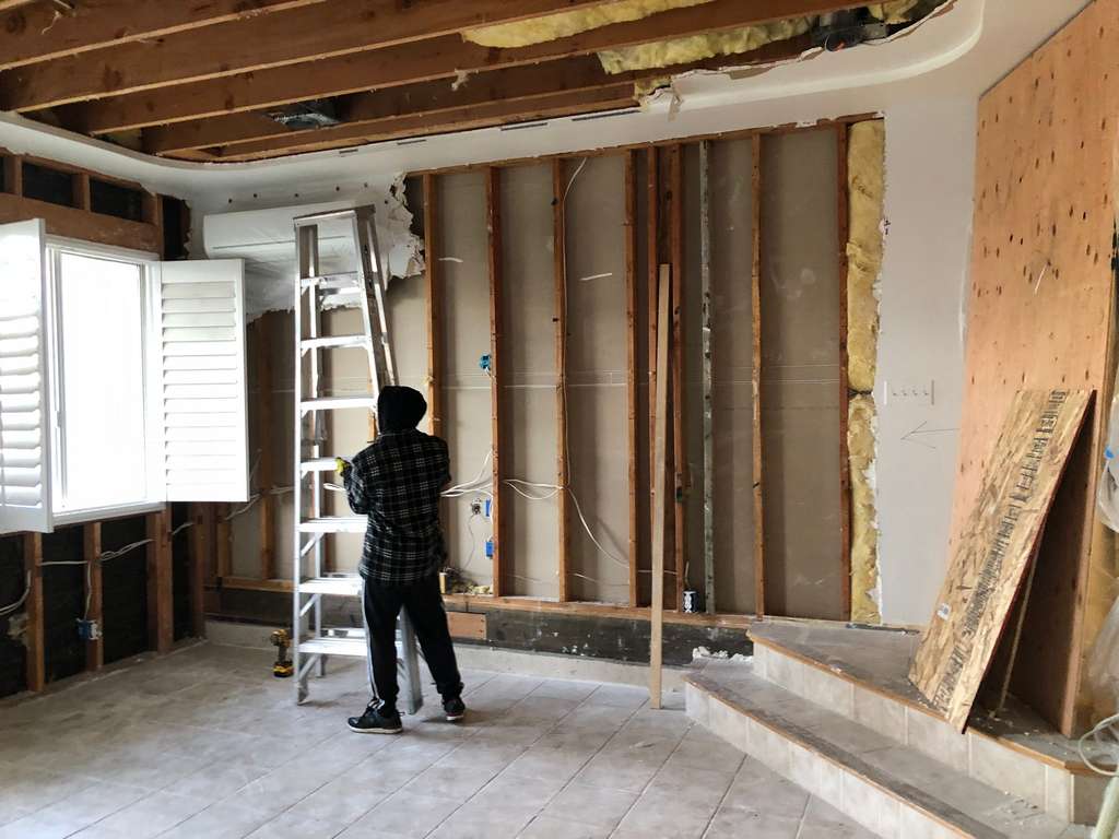 worker removing insulation from the ceiling joist