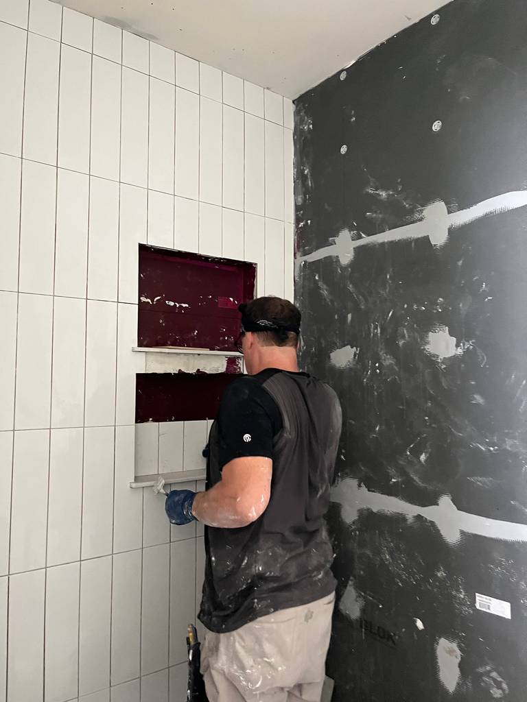 skilled tile worker secusing tile panels on hydro-blok walls