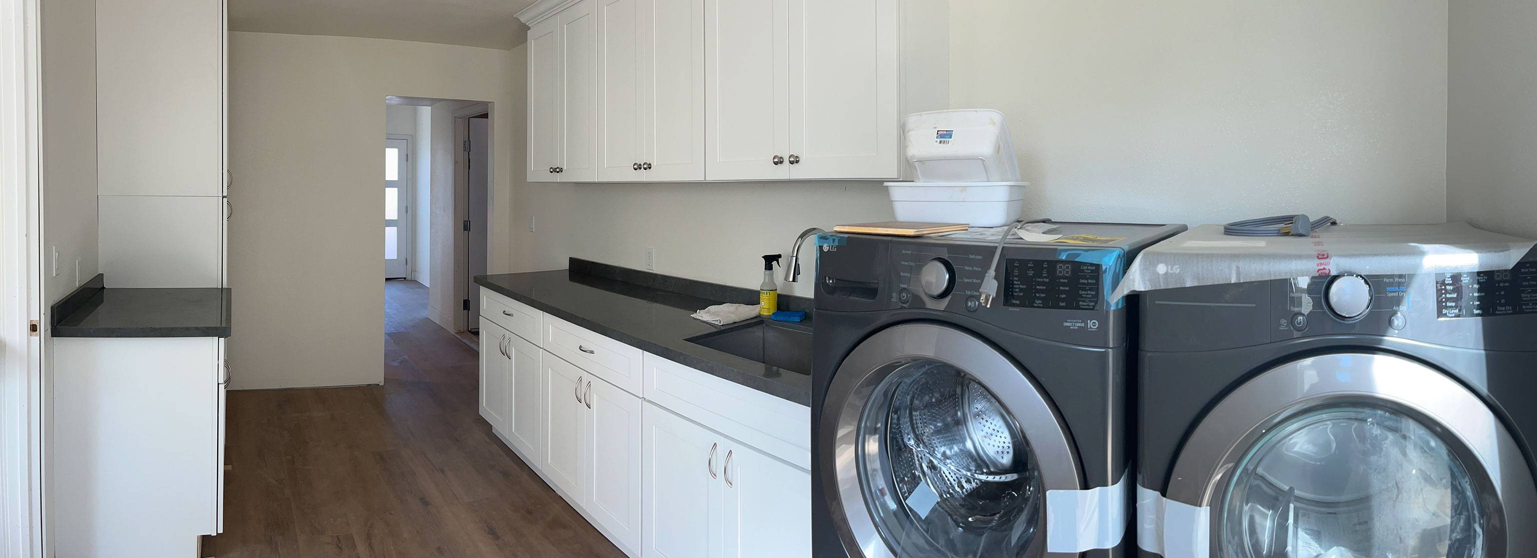 Laundry room nearing completion custom cabinets floor-to-ceiling black marble countertops.