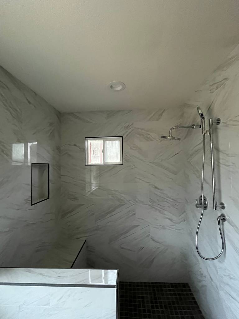 shades of white and gray marble walk-in shower with a niche bench in the home addition's bathroom