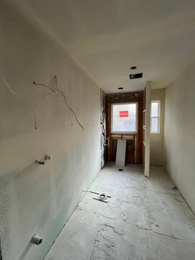 Interior hallway view showing drywall installation and flooring preparation.