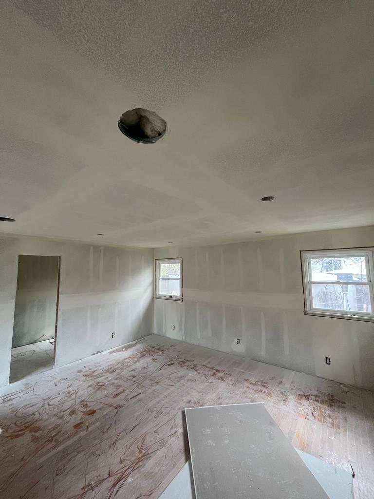 Interior room under construction with unfinished drywall and recessed lighting.