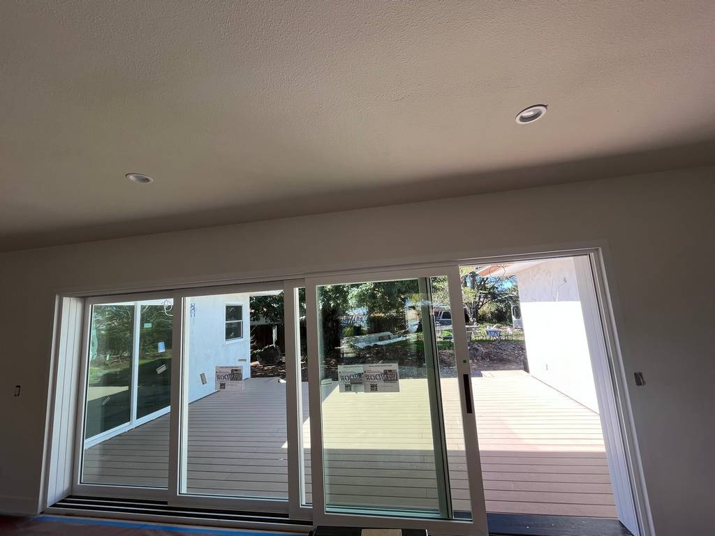Large sliding glass doors installed in residential living room providing access to new backyard deck.